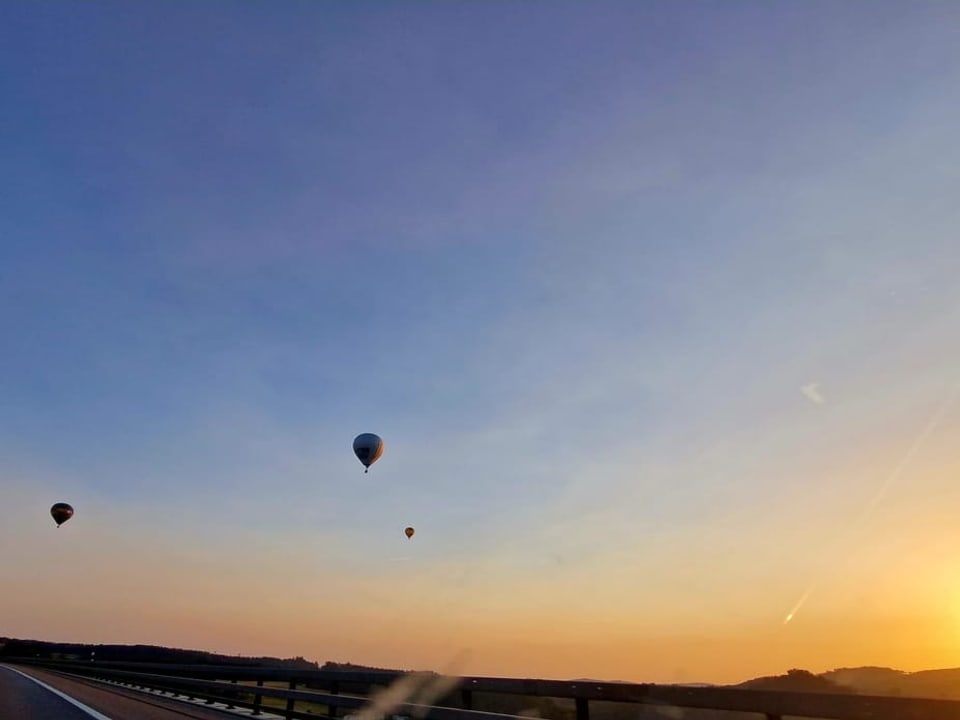 Balloons in the sky with the sun rising.