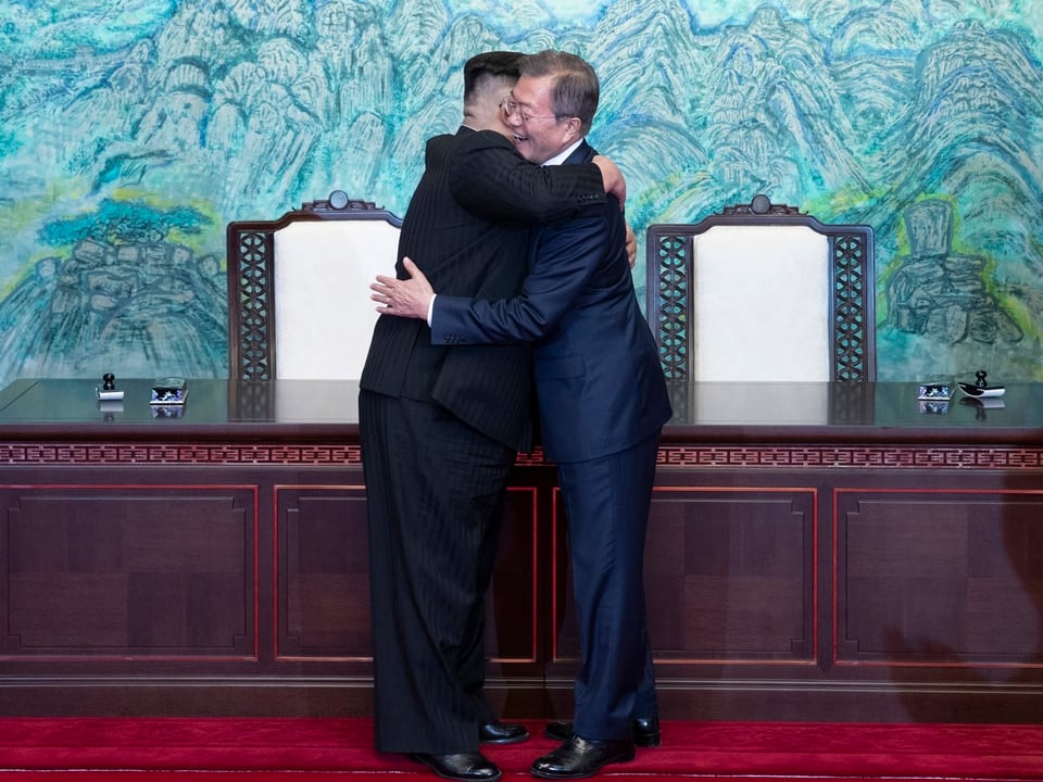 Die beiden Machthaber umarmen sich.