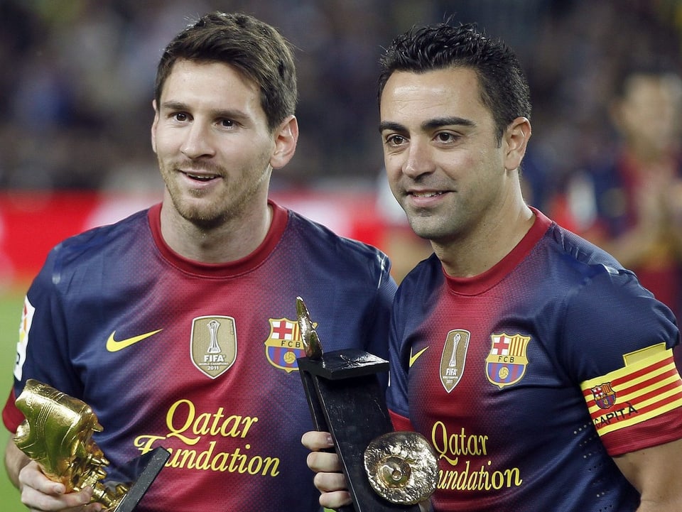 Xavi und Messi posieren mit Trophäen für die Fotografen.