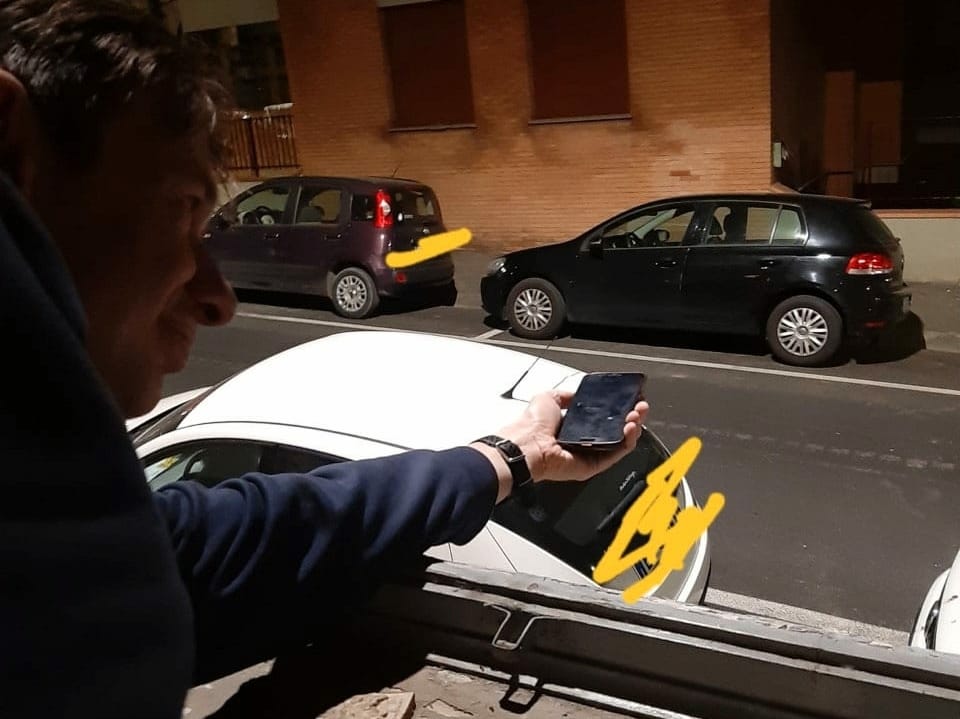 Mann in Italien streckt Handy aus dem Fenster, um Lichtstrahlung zu messen.