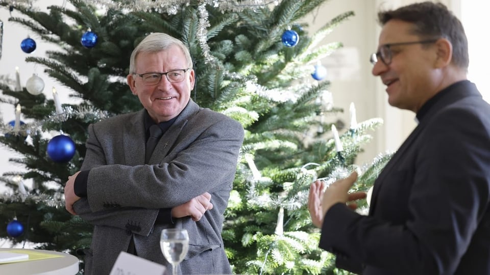 Zwei Männer vor einem geschmückten Weihnachtsbaum.