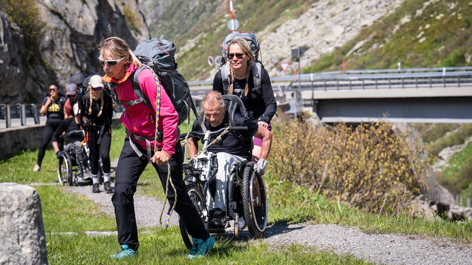 Drei Teams von je einem Rollstuhlfahrer mit zwei Begleitpersonen messen sich bei einem Rennen über die Schweizer Alpen. 