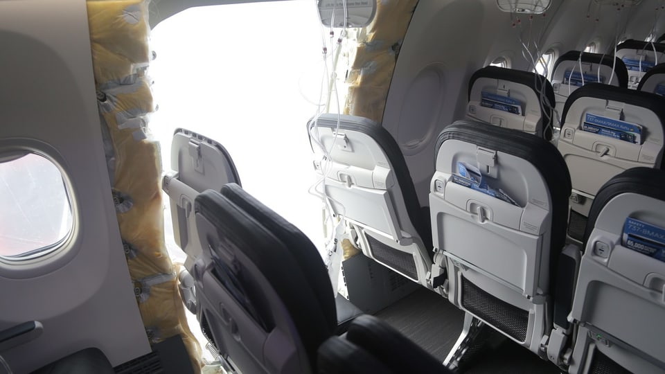Loch klafft in der Flugzeugwand, aufgenommen aus dem Innern des Flugzeuges, Sitzreihen