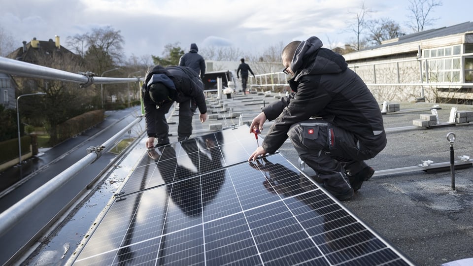 Solartechniker installieren eine Fotovoltaik-Anlage auf einem Dach.