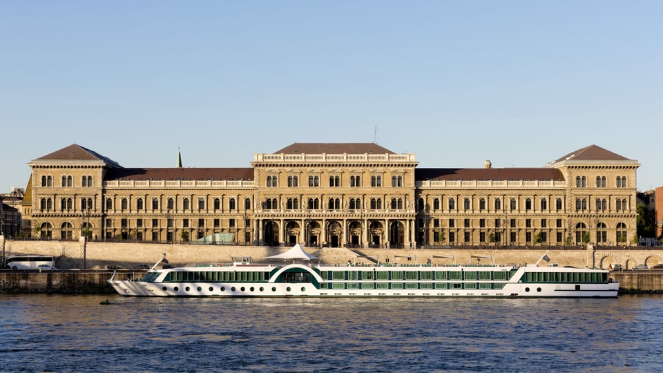 Ein Boot auf einem Fluss und im Hintergrund ein Gebäude.