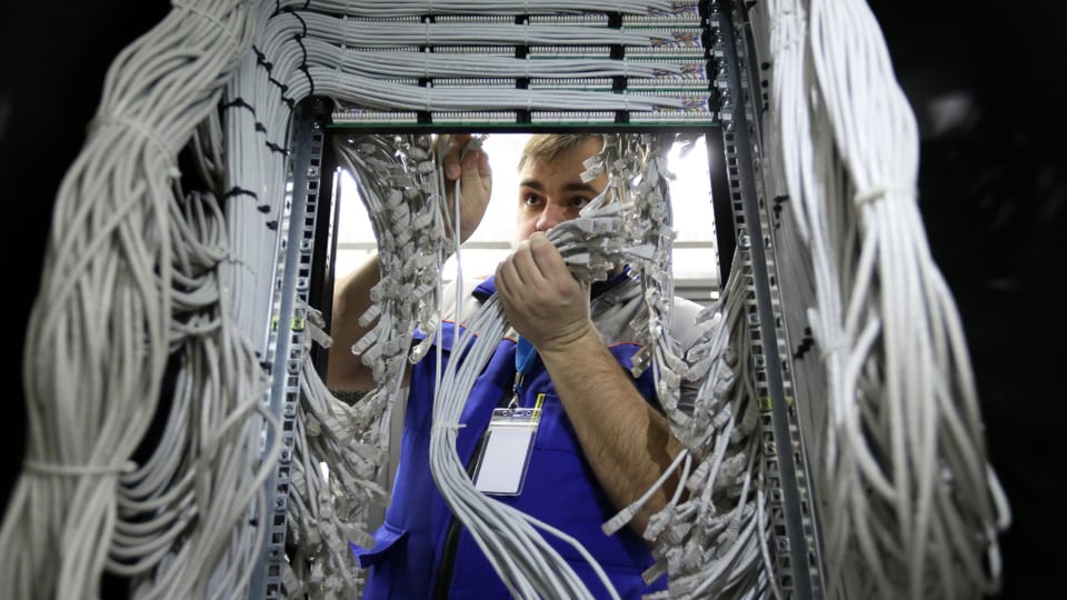 Ein Mann steht inmitten vieler Kabel.