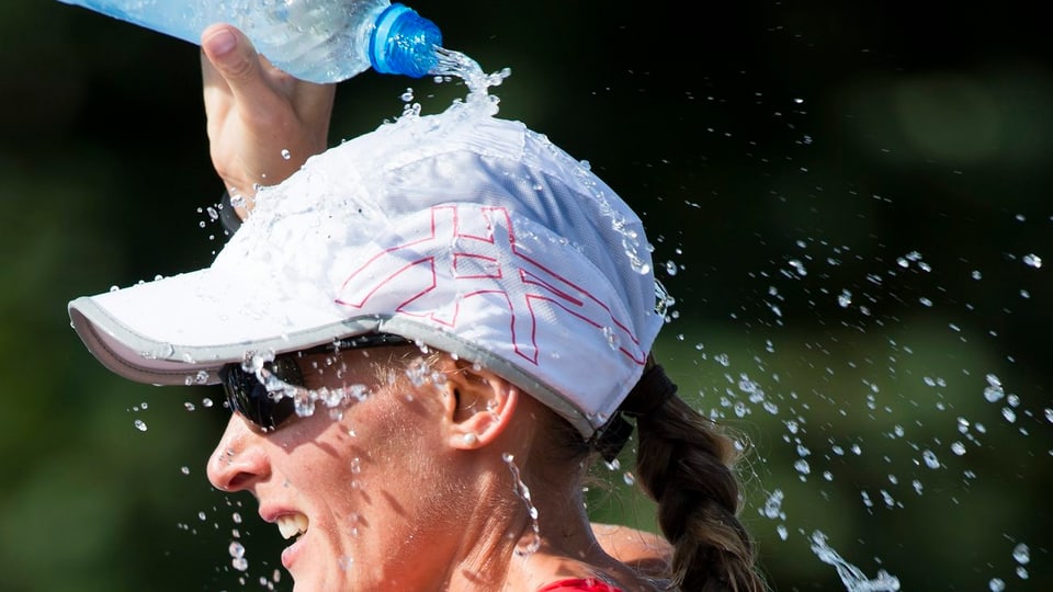 Marie Polli leert sich während eines Rennens Wasser über den Kopf.