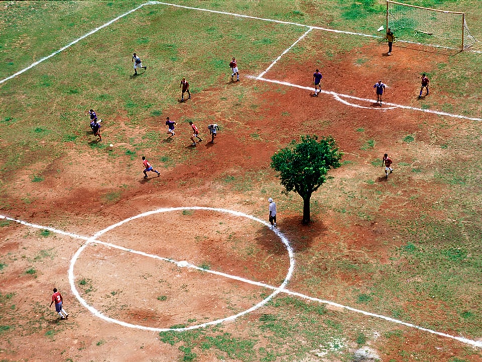 Spärlicher Rasen, rote Erde, fast im Mittelkreis ein Baum: Fussblallplatz in Sao Paulo.