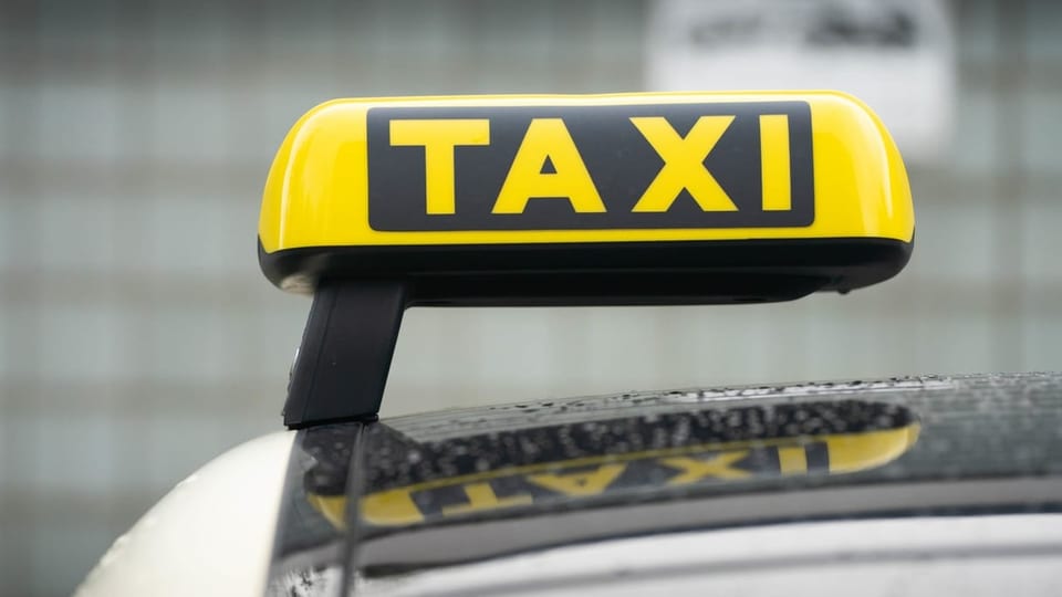 Ein Taxi-Schild ist auf dem Dach eines Fahrzeuges befestigt.