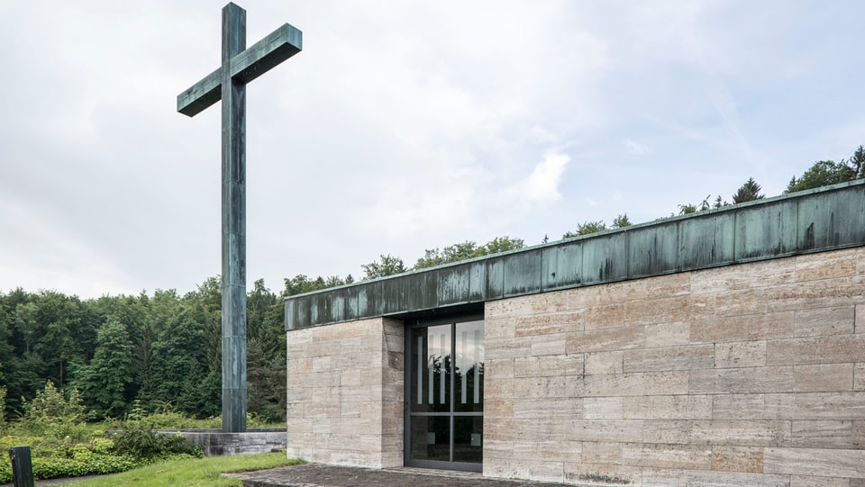 Das Krematorium Nordheim von aussen, neben dem Eingang steht ein grosses Kreuz auf der Wiese.