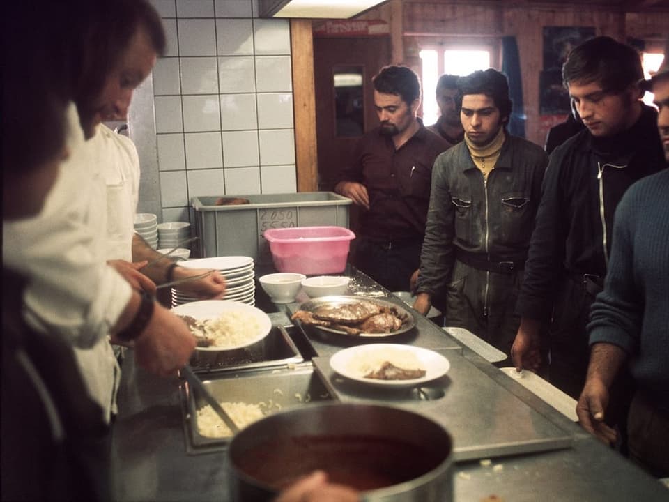 Männer stehen in einer Kantine an