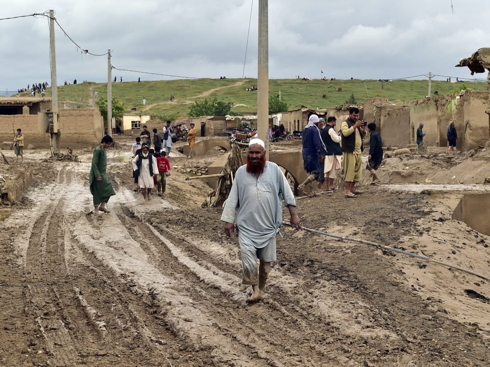 Menschen in einem verschlammten Dorf nach einer Überschwemmung