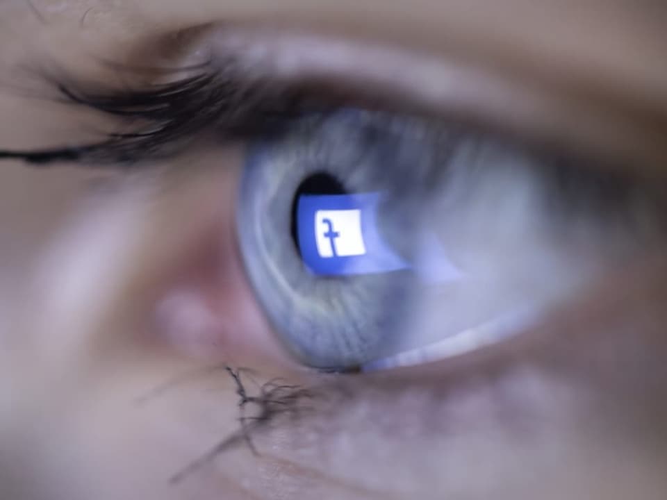 Das Facebook-Logo spiegelt sich in eiem Auge.