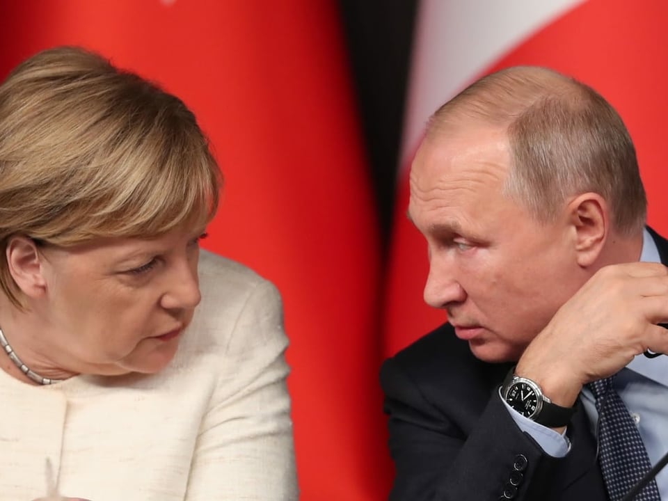 Putin und Merkel stecken die Köpfe zusammen.