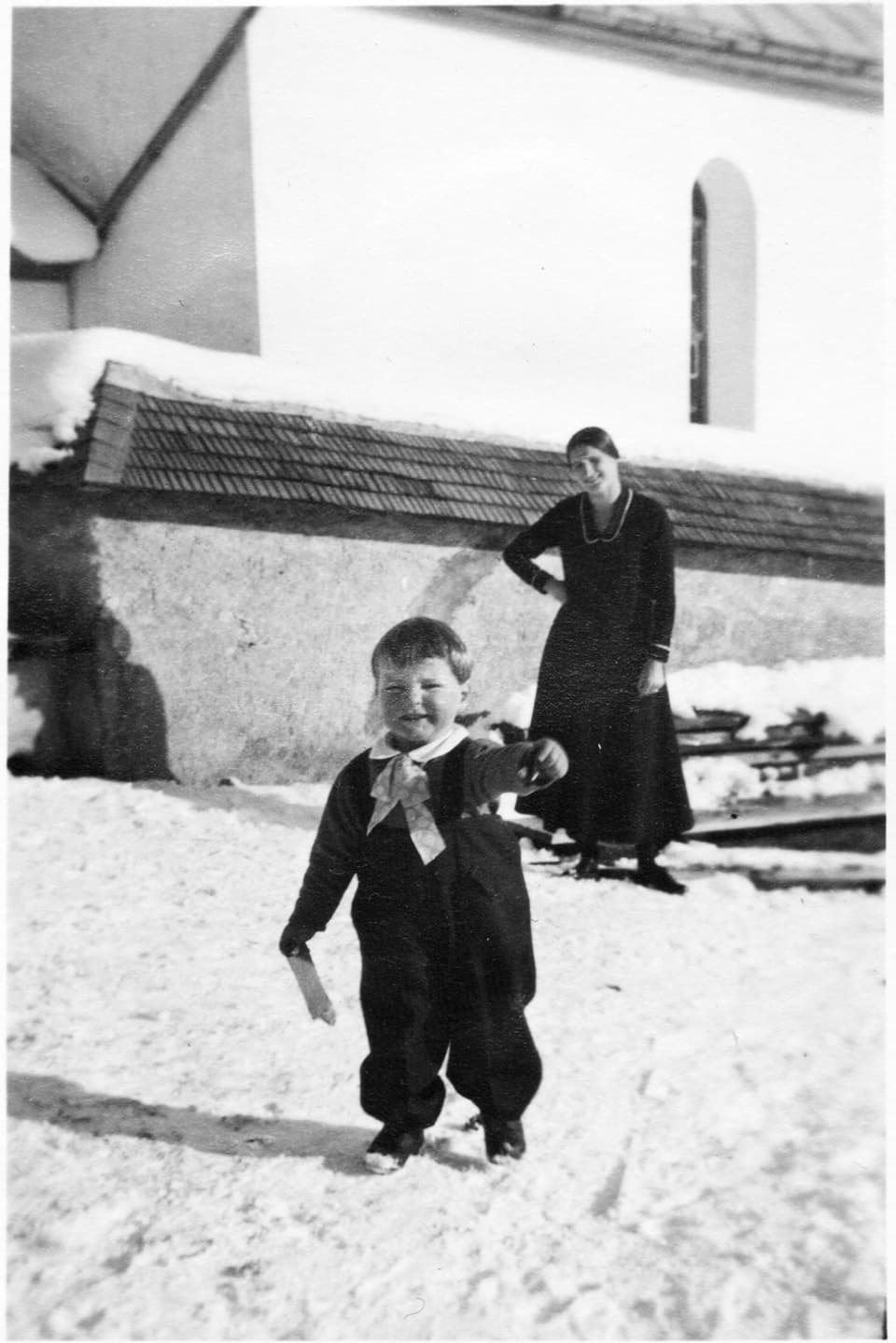 Schwarzweiss-Fotografie einer Frau und eines kleinen Kindes im Schnee.