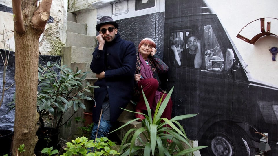 Street-Art-Künstler JR und Agnès Varda vor einer bemalten Wand.