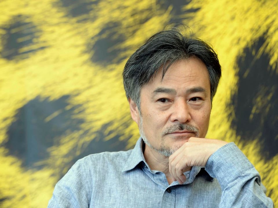 Kiyoshi Kurosawa in einem Gespräch. Im Hintergrund sieht man das gelb-schwarze Leoparden-Fell, das Markenzeichen des Filmfestival Locarno.