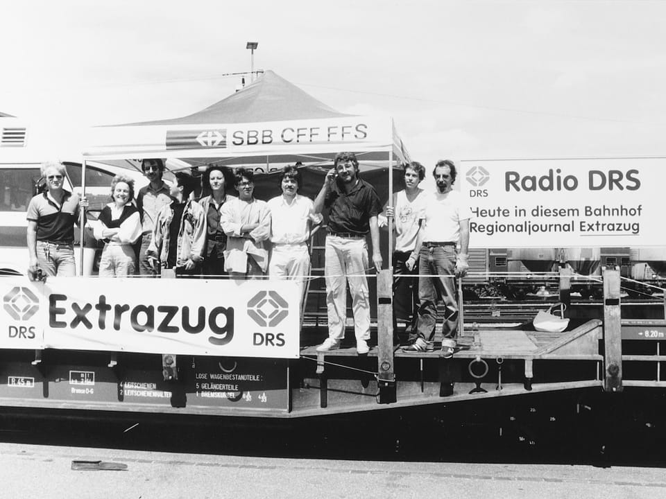 Männer und Frauen auf einer Bühne - darunter ein Banner mit dem Schriftzug "Extrazug"