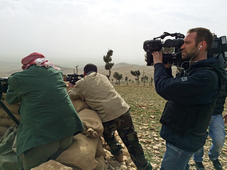 Jesidische Kämpfer beobachten vom Berg aus jede Bewegung im Tal – das Gewehr im Anschlag. Hinter ihnen das Kamerateam von SRF. 