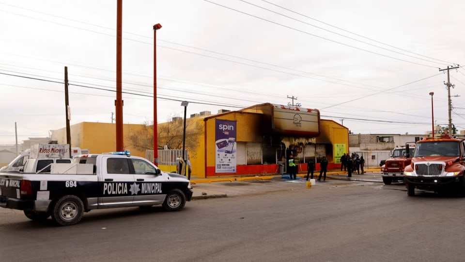 Vor einem kleinen ausgebrannten Einkaufsladen in Mexiko stehen Polizei und Feuerwehr.
