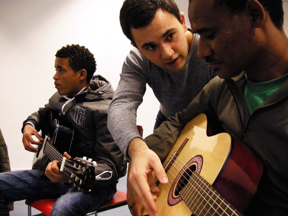 Jugendarbeiter Marco Martina übt mit Flüchtlingen Gitarre spielen.
