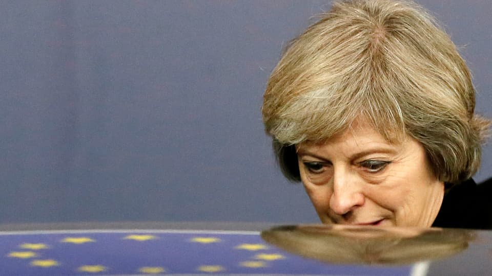 Theresa May steigt in ein Auto ein, auf dem Dach spiegelt sich die EU-Fahne.