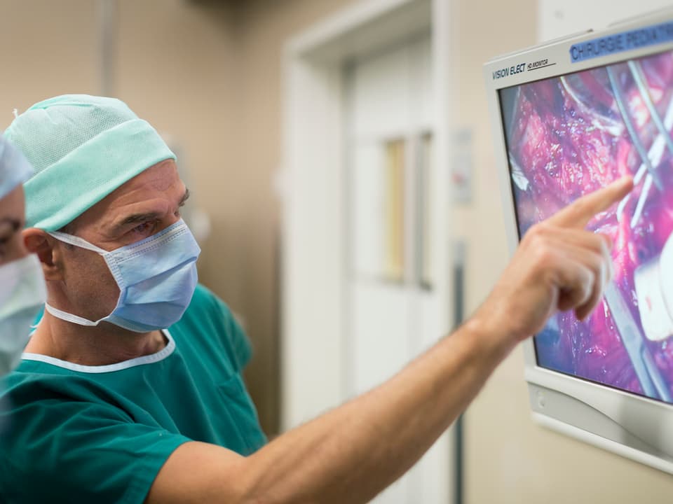 René Prêtre zeigt während der Operation etwas auf einem Bildschirm. 