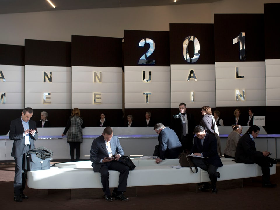 WEF-Teilnehmer prüfen ihre Mobiltelefone im Foyer