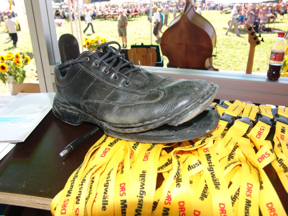 Ein schwarzer kaputter Schueh auf gelben Schlüsselbändern.