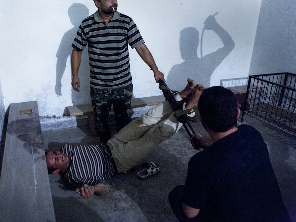 Syrische Oppositionskämpfer foltern einen Informanten mit einer Fussfessel.