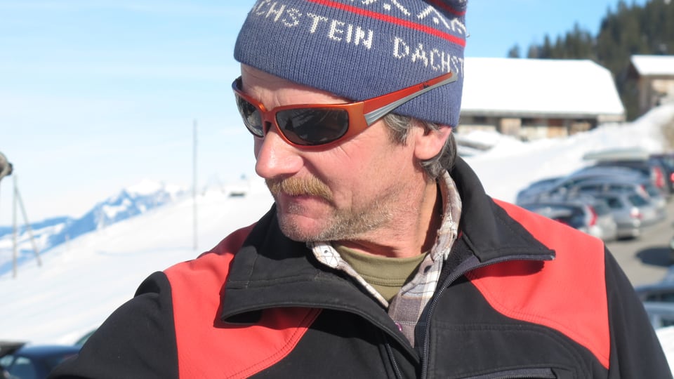 Porträtbild von Ueli Schütz mit Wollkappe und Sonnenbrille. Ueli Schütz arbeitet seit fast 20 Jahren als sogenannter Skiliftbügelgeber im Skigebiet Elsigen-Metsch.