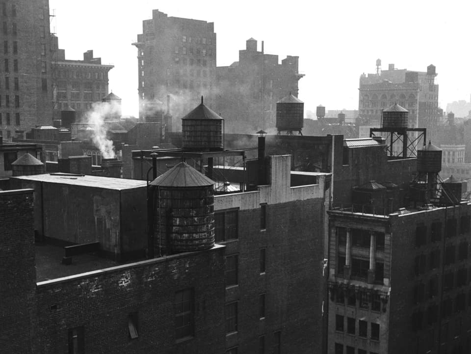 Eine schwarz-weisse Fotografie zeigt die Häuser New Yorks von oben.