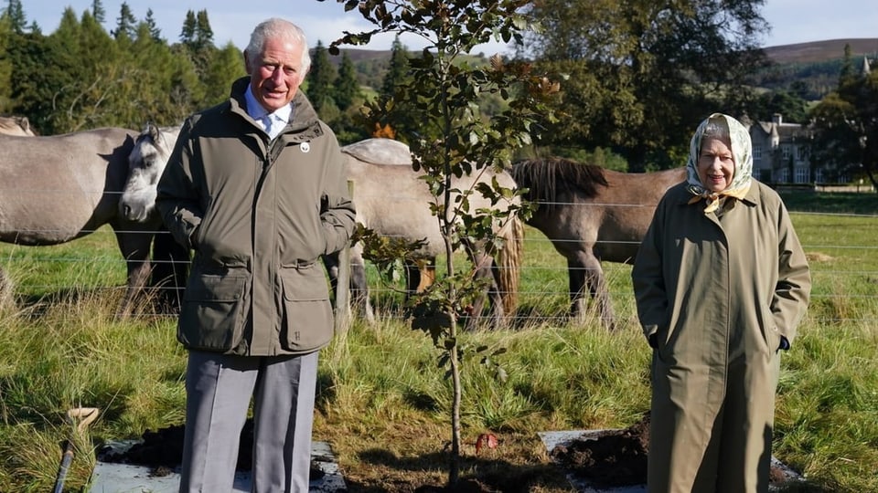 Prinz Charles und Queen Elizabeth posieren neben einem selbst gepflanzten Baum.