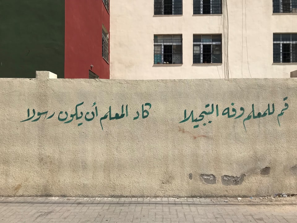 Betonmauer mit einem arabischen Spruch aufgesprayt.