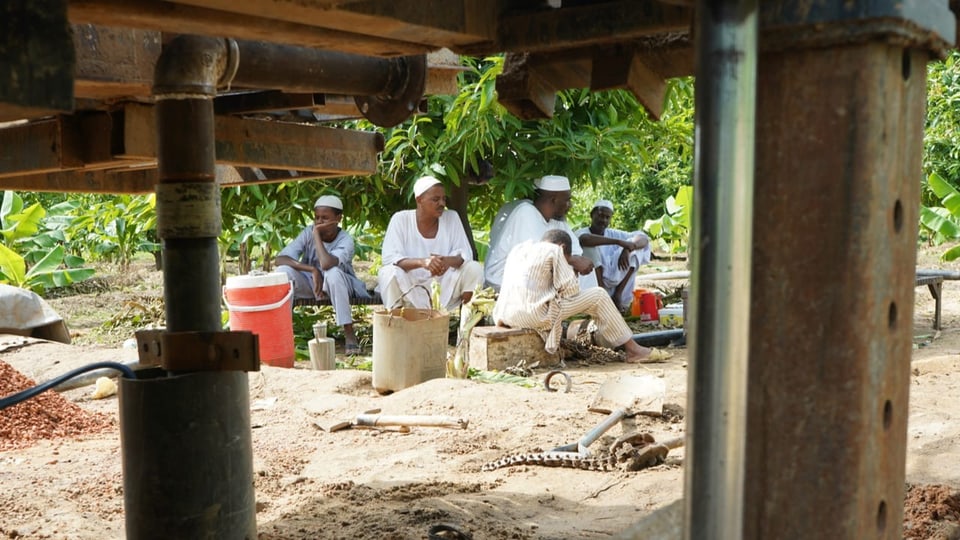 Drei Nilbauern hocken an der Baustelle und trinken Kaffee.