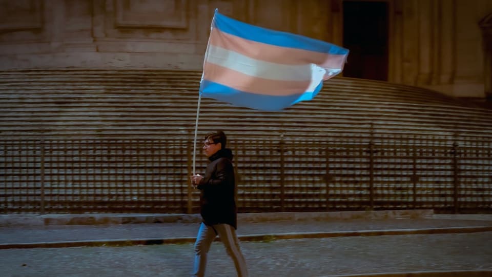 Ein Mann schwenkt eine Transgender-Flagge.