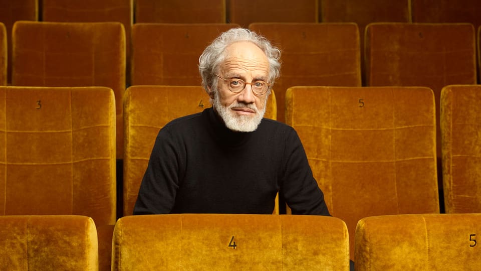 Markus Imhoof in einem Kinosaal mit goldenen Sesseln.