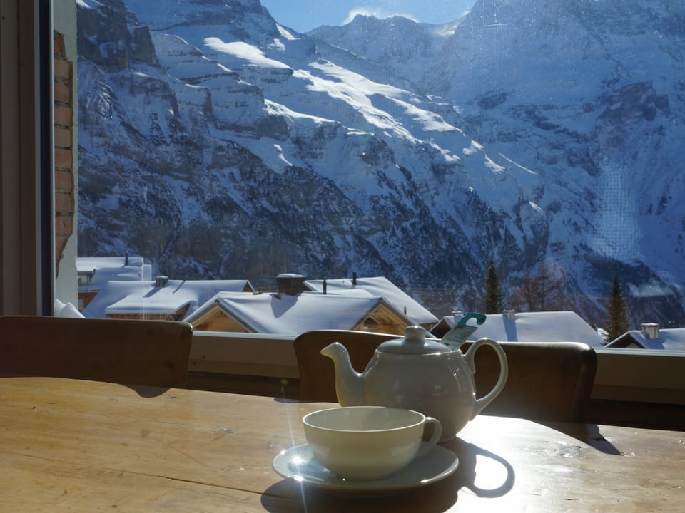 Ein Teekrug steht vor einem Fenster mit schöner Bergsicht.