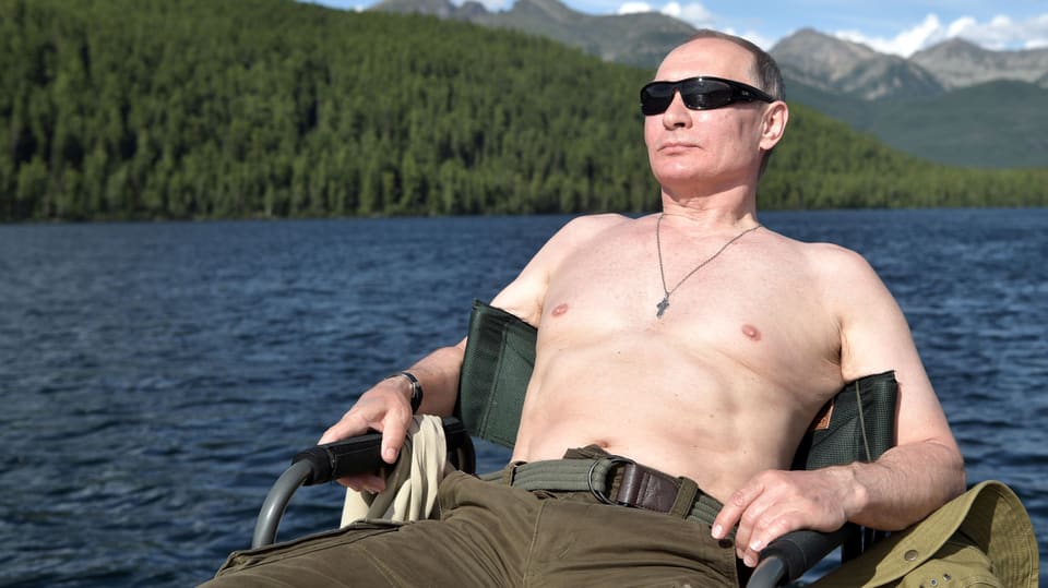 Putin sonnt sich auf einem Stuhl, hinter ihm ein Bergsee. (5. August 2017)