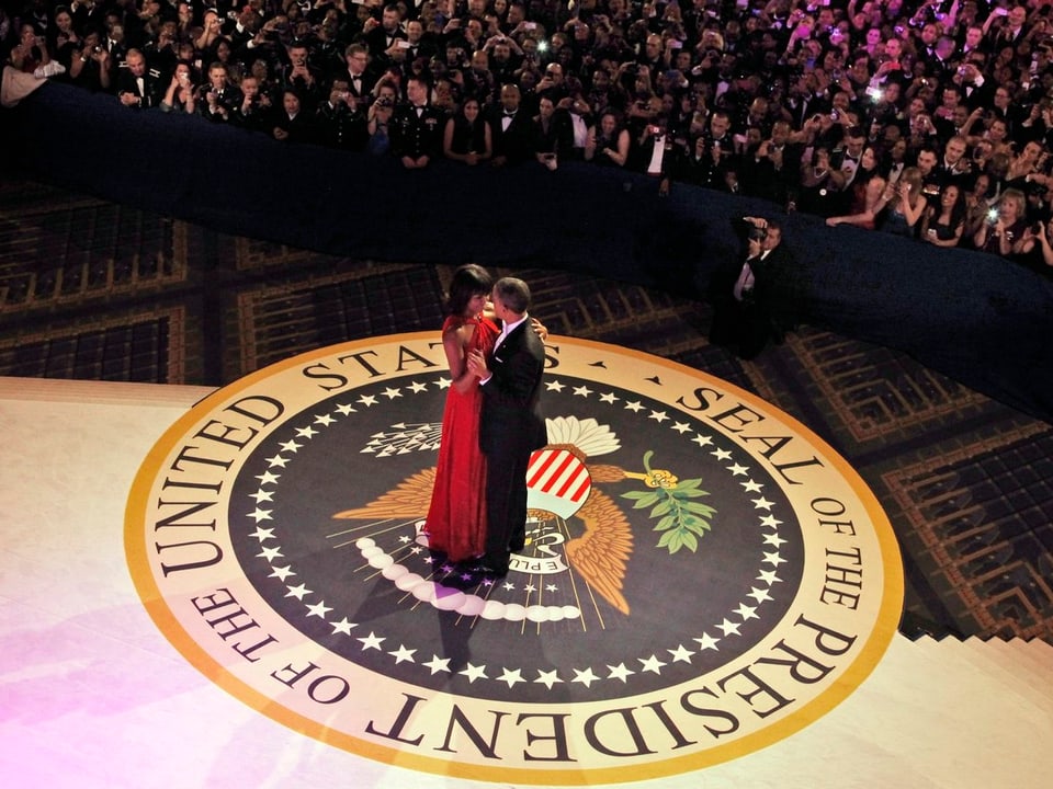 Das Präsidentenpaar tanzt auf der Bühne vor einer Meute von Fotografen.