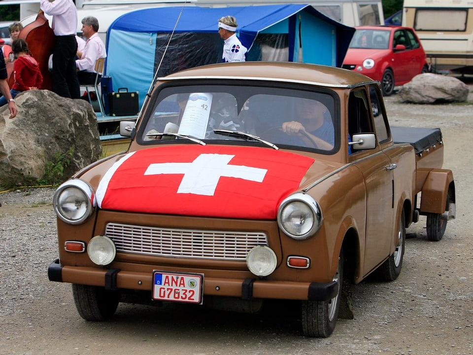 Trabant mit einer Schweizer-Fahne auf der Motorhaube.