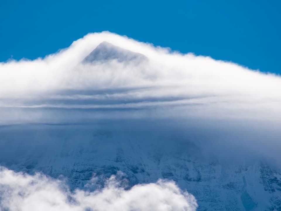 Pyramidenförmiger Berg mit lustigen Wolken in Streifenmuster an der Vorderseite. 