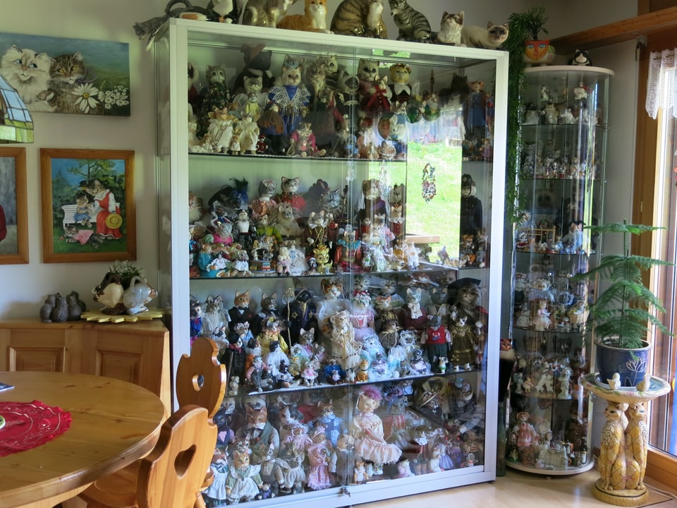 Ein Schrank voll mit Puppen und Katzenfiguren. 