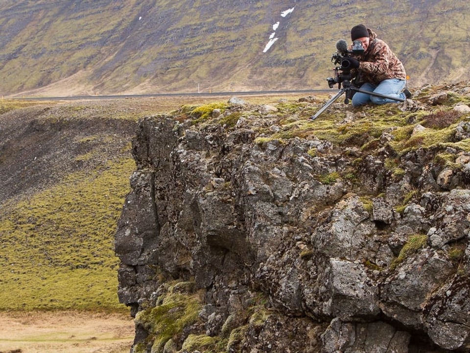 Ein Kameramann auf einem Felsvorsprung in einer kargen Landschaft.