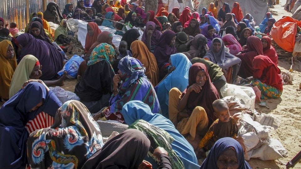 Frauen und Kinder sitzen in einem somalischen Flüchtlingscamp am Boden.