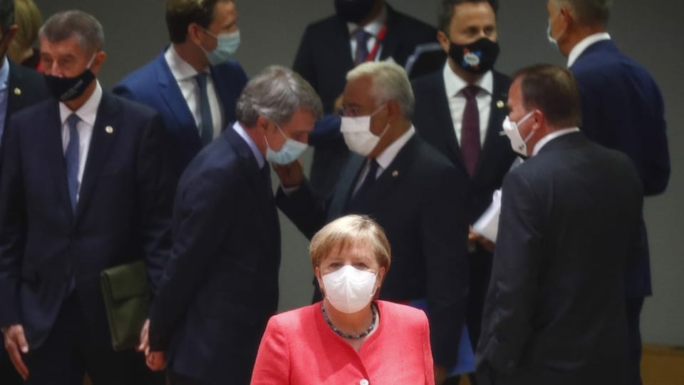 Merkel in rosa, im Hintergrund Männer in schwarz