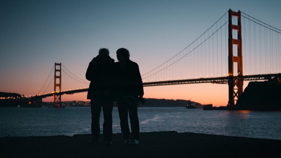 Ein Paar im Gegenlicht: Umrisse vor der Golden Gate Bridge, schauen aufs Wasser.