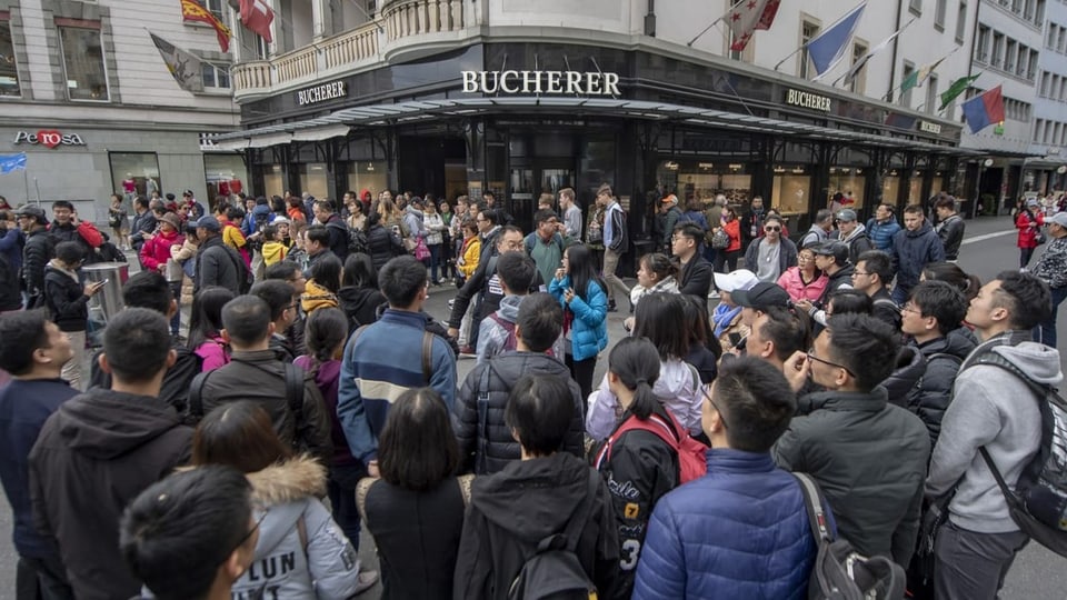 Chinesische Touristengruppe vor einem Uhrengeschäft.