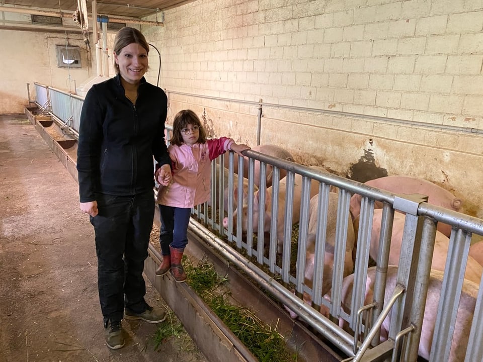 Silvia Ineichen steht mit ihrer Tochter im Schweinestall.
