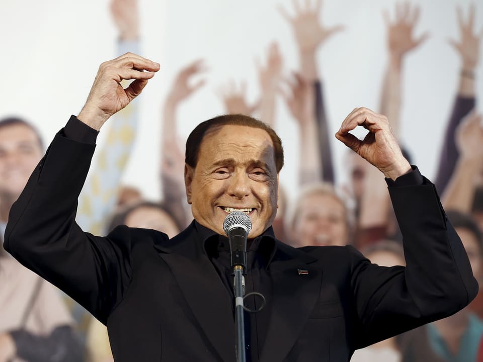 Silvio Berlusconi bei einer Rede - hinter ihm jubeln seine Anhänger. 